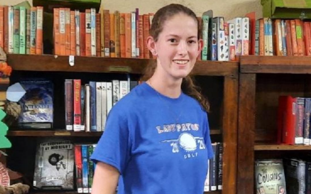Photo of Alanna standing in front of bookshelves